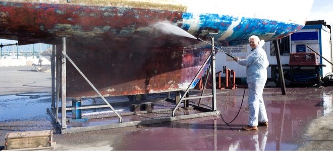 Hombre feliz lavando a presión el fondo de un gran velero