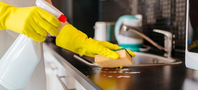 manos con guantes limpiar la superficie con spray y esponja