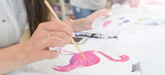 Mujer pintando flamenco rosa sobre tela para camisa
