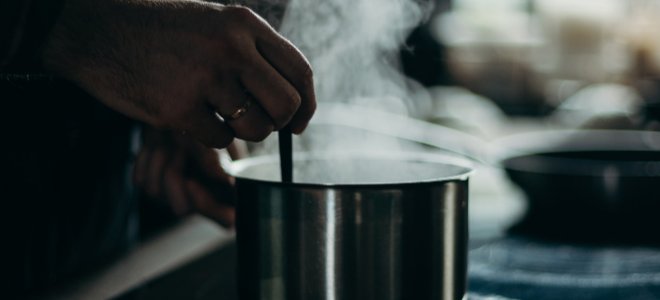 mano revolviendo líquido humeante o hirviendo en una olla