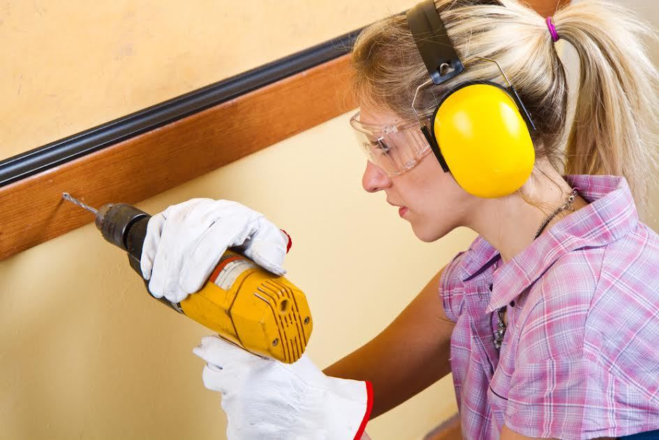 Una mujer que usa un taladro.