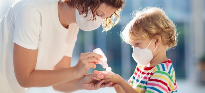 madre poniendo desinfectante de manos en las manos de un niño