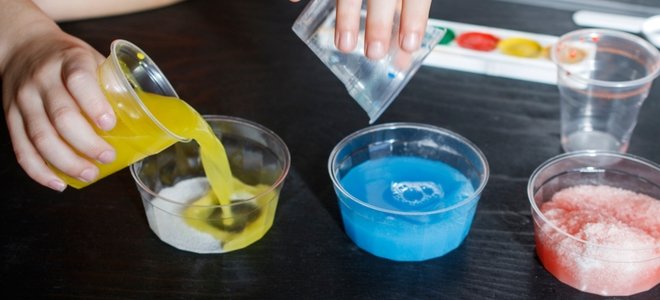 vertiendo colores de pintura en la nieve en tazas