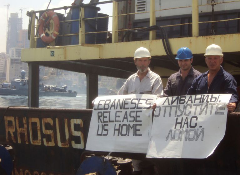 El capitán del 'Rhosus', Boris Prokoshev, y miembros de su tripulación muestran pancartas pidiendo su liberación en la embarcación que portaba 2.750 toneladas de nitrato de amonio, en el puerto de Beirut, en 2014.