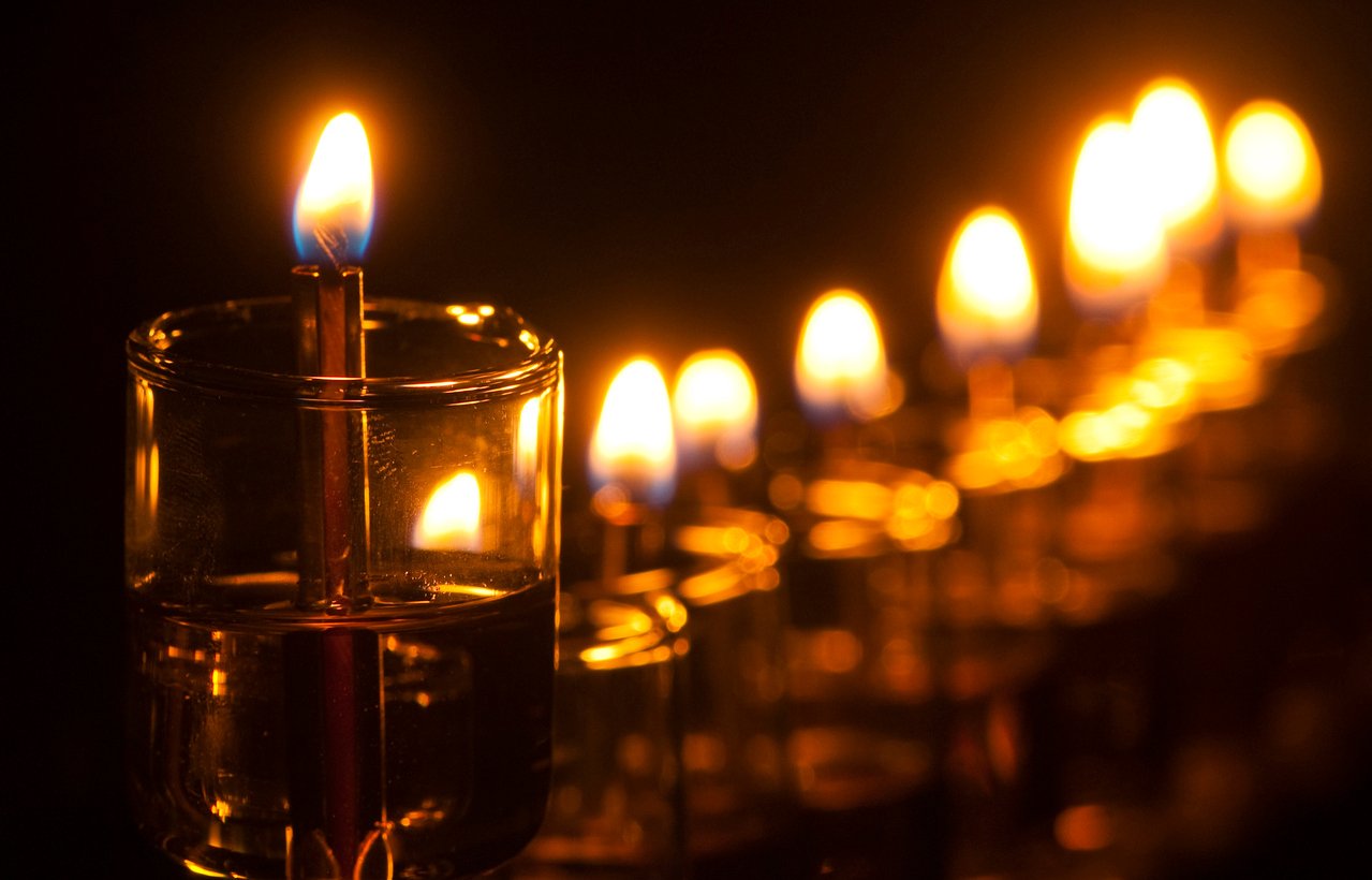 Una fila de velas de aceite encendidas en una menorá.