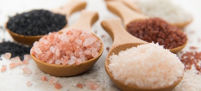 Cuatro sales de colores en cucharas de madera.