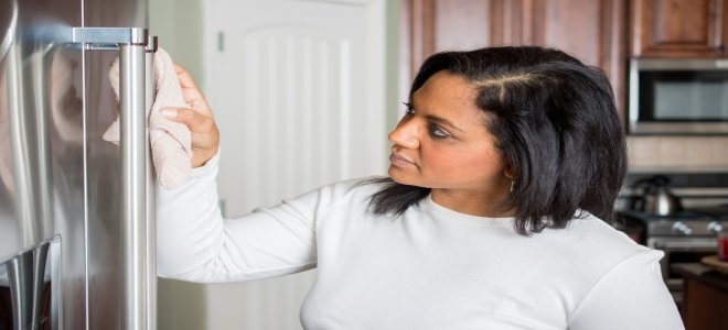 Una mujer puliendo un frigorífico de acero inoxidable. 