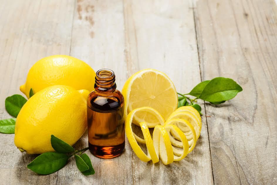 Limones junto a pequeñas botellas de aceite esencial. 