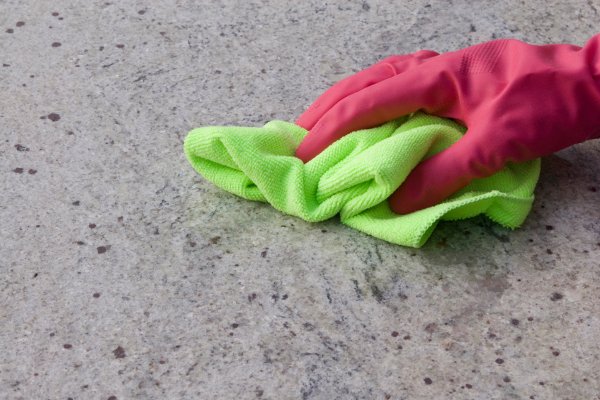 Un par de guantes rosas con un paño verde sobre un mostrador de granito. 