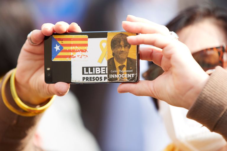 Una mujer toma una foto durante una manifestación, en la que exhibe una pegatina del expresidente Carles Puigdemont