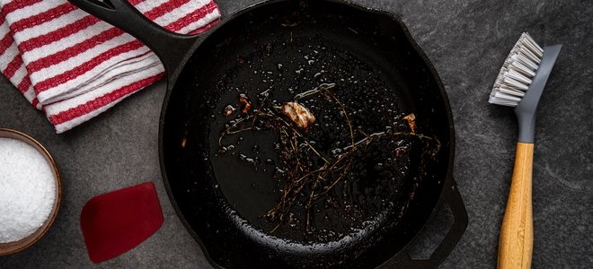 sartén de hierro fundido sucio con implementos de limpieza