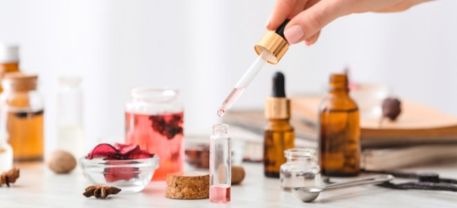 Mano haciendo perfume casero con un gotero líquido.