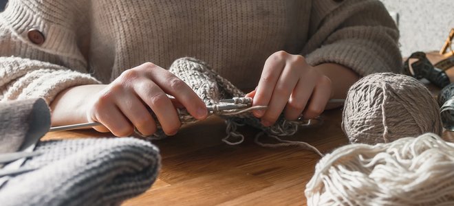 manos tejiendo con hilo y agujas