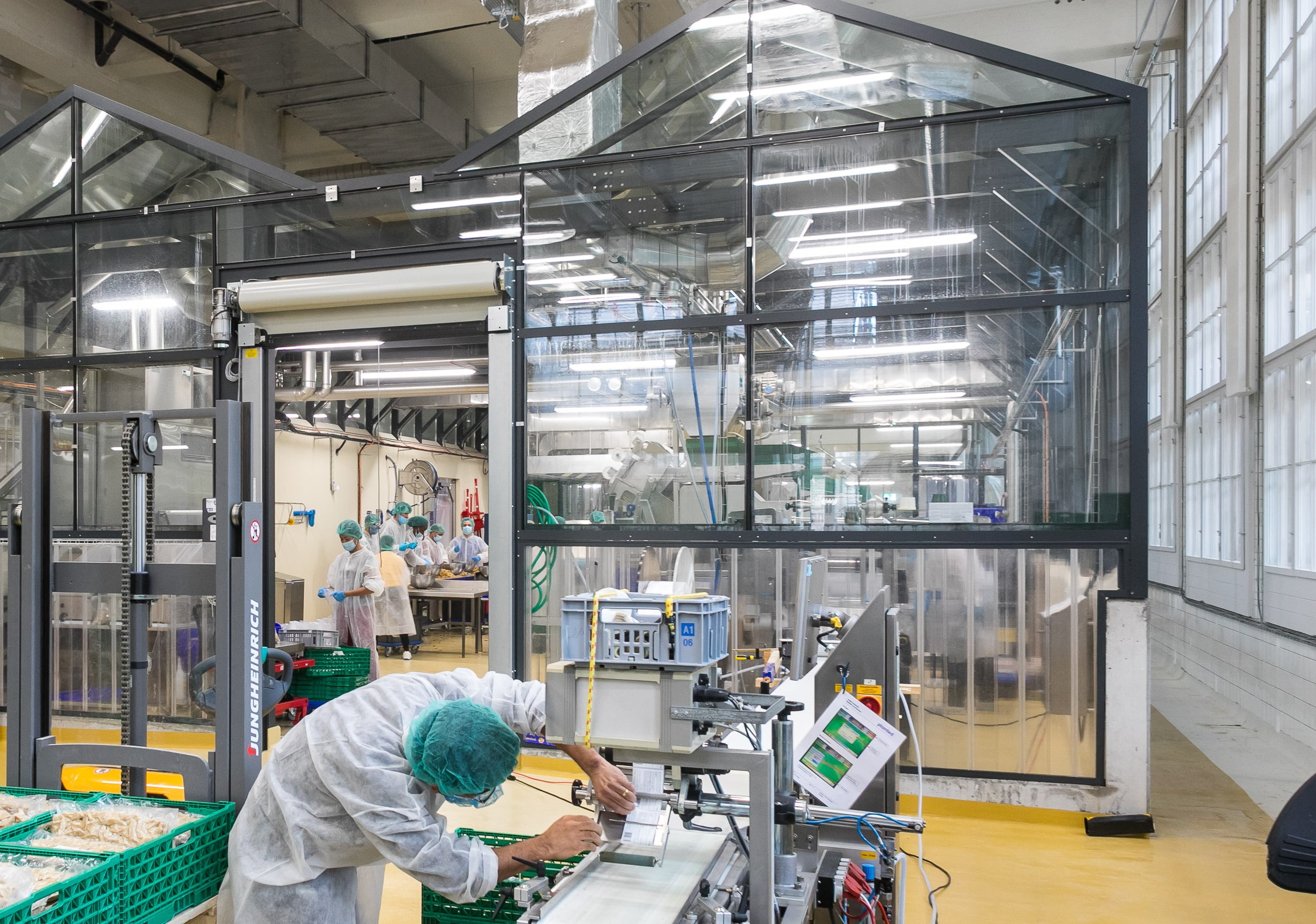 Un gran entorno de laboratorio con paredes transparentes.  Una persona trabaja en maquinaria en primer plano.