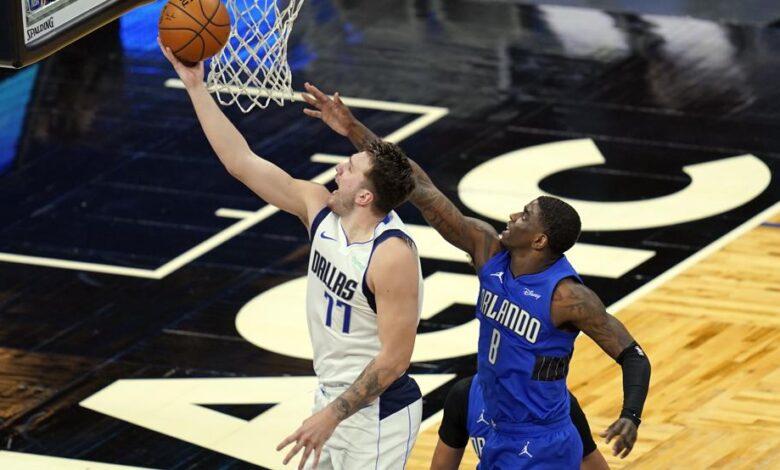 Luka Doncic anota una bandeja fácil ante la tímida oposición de Dwayne Bacon en la victoria de Dallas frente a Orlando