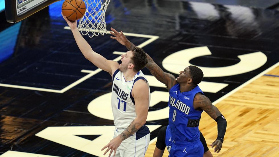 Luka Doncic anota una bandeja fácil ante la tímida oposición de Dwayne Bacon en la victoria de Dallas frente a Orlando