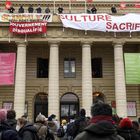 Demonstrators gather as members of the performing art branch of the French national trade union General Confederation of Labour (Confederation Generale du Travail - CGT) hang banners and flags from the balcony of the French Theatre Odeon theatre de l'Europe, in Paris, on March 5, 2021 to ask for the reopening of cultural places, a year after the first closing measures to curb the spread of the Covid-19 pandemic. (Photo by Bertrand GUAY / AFP)