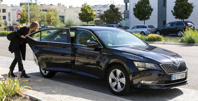 Una mujer abre la puerta de un coche VTC de Cabify.
