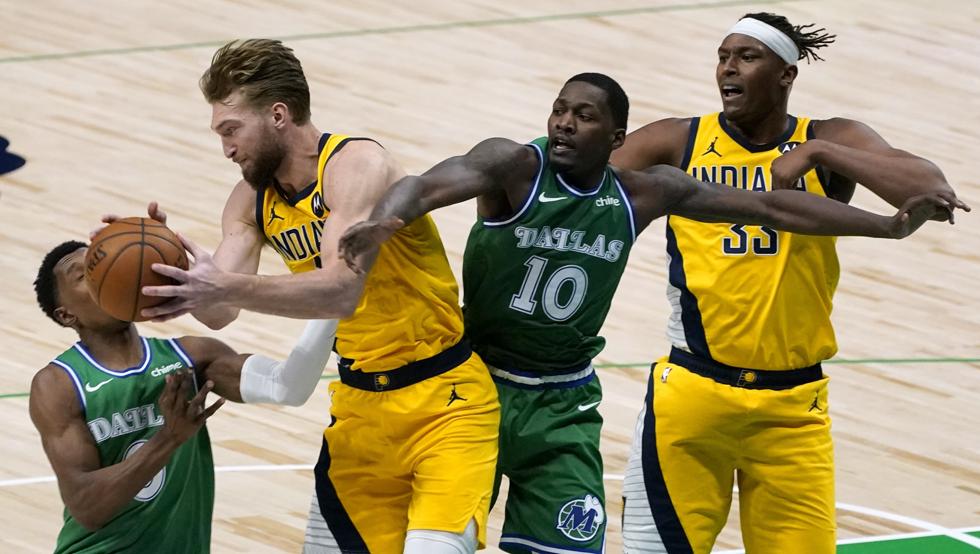 Domantas Sabonis lucha por un balón con Josh Richardson y Dorian Finney-Smith en la victoria de Indiana en Dallas.