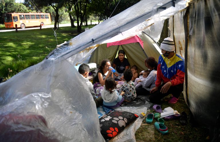 Migrantes venezolanos comen dentro de una carpa en un campamento improvisado en Bogotá, en junio de 2020.