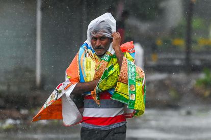 Un hombre se protege con plásticos en una calle de Amreli, en el estado de Gujarat, este martes.