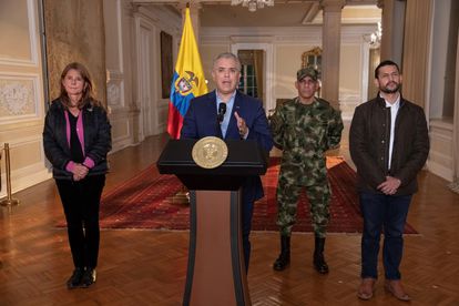 Fotografía cedida por la presidencia de Colombia que muestra al mandatario Iván Duque (c) mientras pronuncia un discurso televisado en el que anuncia que el ejército patrullará las ciudades donde se están produciendo disturbios.