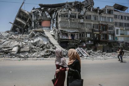 Varias personas pasan frente a un edificio destruido por los bombardeos en Gaza.