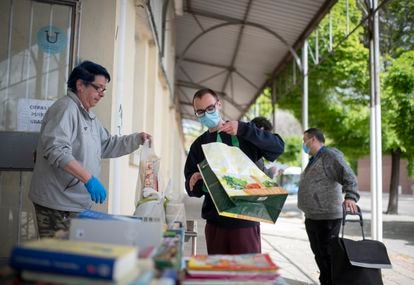 Varias familias esperan en la cola del centro de voluntario de caritas en Orcasur para recoger alimentos.