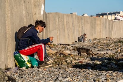 Dos chicos marroquíes aguardan escondidos en la playa ceutí de Calamocarro.