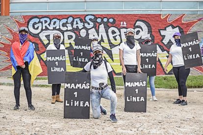 Algunas de las mamás de primera línea al frente de un mural en su honor.