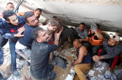 Unos ciudadanos rescataban a una niña de entre los escombros de un edificio derruido, este domingo en la ciudad de Gaza.