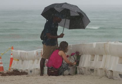 Una mujer coloca flores cerca del edificio derrumbado en Surfside, este sábado.