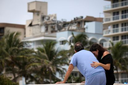Una pareja frente al edificio parcialmente derrumbado en Surfside, Miami.