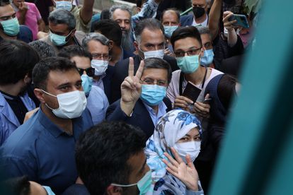 El moderado Hemmati, hace el signo de la victoria en el exterior del colegio electoral junto a su mujer (con un pañuelo de flores)
