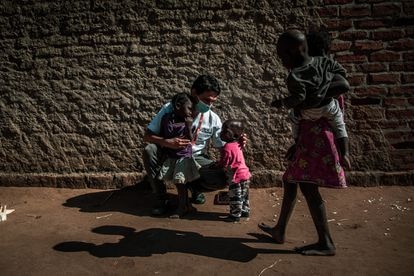 El doctor Hansel Mundaca distrae a unos niños en el barrio 24 de Julho de Mopeia mientras sus padres atienden a los encuestadores del Proyecto Bohemia. Mundaca es uno de los investigadores médicos de este ensayo clínico, de marca española, que busca demostrar si la ivermectina, un fármaco muy usado para otras dolencias, es eficaz para matar al mosquito y reducir la incidencia de la enfermedad. Pincha en la imagen para ver la fotogalería completa.