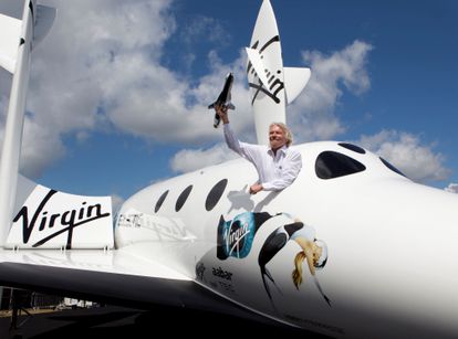 Richard Branson posa para la prensa desde una réplica de SpaceShipTwo, una de las naves de su copañía Virgin Intergalactic.