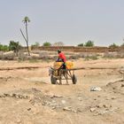 <b>Un carro cargado con garrafas de agua atraviesa el cauce seco de un río a la entrada de Boully.</B> En la ciudad de Boully, a pocos kilómetros del imponente río Senegal, que hace de frontera natural entre el país mauritano y el senegalés, se está viviendo un “tsunami”. “Esto es un tsunami [de personas que emigran]. Muchísima gente se va porque aquí ya no puede ganarse la vida. Sobre todo los jóvenes, que creen que su futuro aquí no existe. Hay que hacer algo, porque sin jóvenes un pueblo no crece”. Quien habla es uno de los ancianos de esta ciudad de 10.000 almas. Nos explica que la mayoría huyen hacia destinos cercanos pero que algunos han emprendido el viaje hacia Europa. “No sé si lo han conseguido o no, pero aquí no han vuelto”.