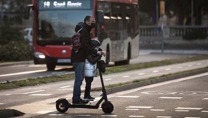 Un hombre circula con un niño en patinete, en enero.