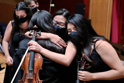 Los miembros de la Orquesta del Encuentro se abrazan al concluir su último concierto en el Auditorio Alfredo Kraus de Las Palmas de Gran Canaria.