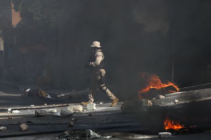Un policía despeja una carretera bloqueada por manifestantes en el barrio Lalue de Port-au-Prince, Haití, el miércoles 14 de julio de 2021.