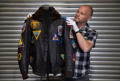 Un hombre muestra la cazadora original lucida por Tom Cruise en 'Top Gun' durante una subasta celebrada en diciembre de 2020.