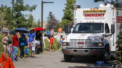 Un vehículo de emergencias junto a la cola de personas que esperan para entrar en un parque acuático y combatir el calor, en Calgary (Canadá).