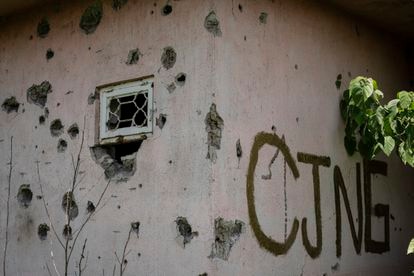La fachada de una casa agujereada por impactos de bala junto a una pintada con las siglas del Cartel Jalisco Nueva Generación (CJNG) en El Limoncito, en el municipio de Aguililla.