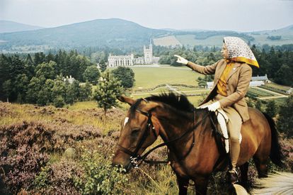 La reina Isabel II a caballo mirando hacia el Castillo de Balmoral, Escocia, a lo lejos, durante las vacaciones de verano anuales de la Familia Real, en septiembre de 1971.