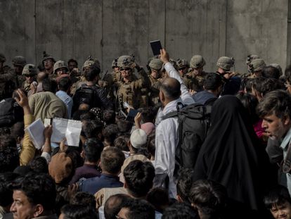 Un hombre sujeta su pasaporte delante de los militares que guardan el aertopuerto de Kabul.