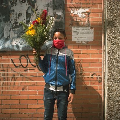 Un niño posa con unas flores que compró para el cumpleaños de su madre en Caracas, el 24 de agosto de 2020.