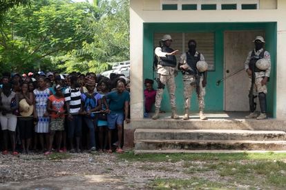 La policía de Haiti resguarda la escuela durante la entrega de alimentos.