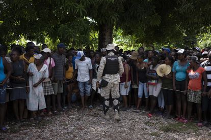 Un policía controla la fila de personas durante la entrega de alimentos.