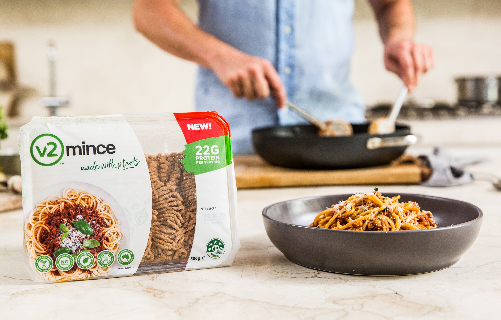 Un paquete de carne molida de v2Food y alguien cocinándola en la cocina.