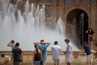 Varios jóvenes se refrescan en la fuente de la plaza de España en Sevilla, este martes.